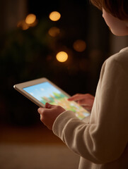 Young child carefully holding tablet, engaged with screen. boy playing game in cozy home at night with warm, glowing light background for calm mood