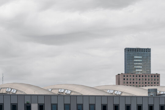 Industrial rooflines and high-rise buildings under cloudy sky in Frankfurt, Germany, capturing balance between functional architecture and urban density