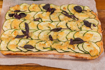 Cooked zucchini pizza on parchment on cutting board close-up