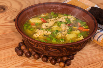 Hot vegetable soup with meat in clay bowl close-up