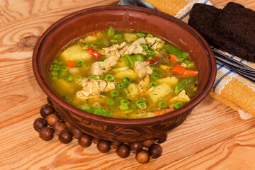 Serving of hot vegetable soup with meat in clay bowl
