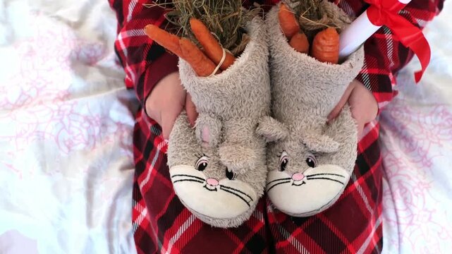 Childrens gifts in shoes. St Nicholas Day. Children's shoes in the shape of a rabbit, filled with hay, carrots for the arrival of St. Nicholas. A wish bundle wrapped in red ribbon