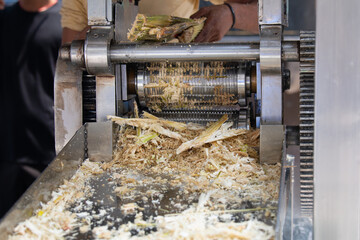 Sugarcane juicing machine on a market stall in India, fresh pressed juice from stalks, squeeze the...
