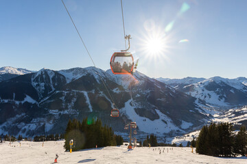 Sunny winter day on alpine slope with skis and snowboards resting near gondola station. Bright sunlight, blue sky, and mountain panorama create atmosphere of adventure, freedom, and relaxation