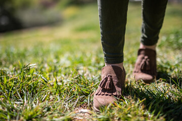 Stylish suede ankle boots walking on a sunny green grass lawn, perfect for fashion blogs or outdoor lifestyle campaigns, moccasin style with a casual vibe