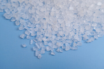 Macro view of coarse white granular crystals, ideal for showcasing ingredients like sea salt or Epsom salt used in food preparation, spa treatments, and health supplements, set against a bright blue t