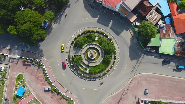A perfect top-down aerial view of the President Francisco Xavier do Amaral roundabout in Dili, Timor-Leste. This bird's-eye perspective captures the perfect circular pattern of traffic.