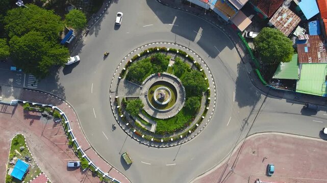 A perfect top-down aerial view of the President Francisco Xavier do Amaral roundabout in Dili, Timor-Leste. This bird's-eye perspective captures the perfect circular pattern of traffic.