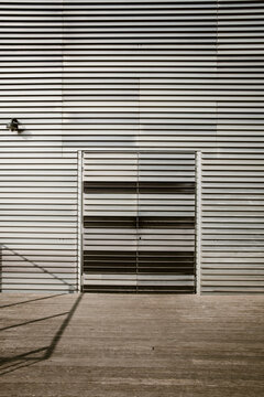 Minimal metal facade with parallel horizontal lines and gate openings revealing order, proportion, and balance in architectural composition and surface rhythm