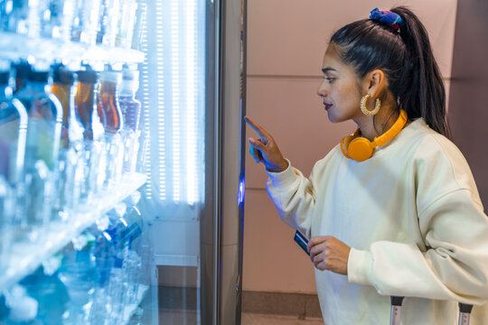 Solo traveler buying snack at airport vending machine in casual clothing