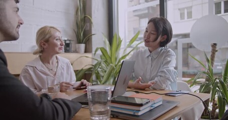 Diverse colleagues brainstorm and analyze data in a co working space coffee bar. They collaborate on a startup project, using a laptop and notes. - Powered by Adobe