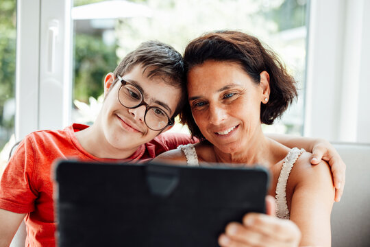 Mother and son with trisomy 21 smiling and learning together at home