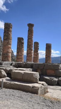 Ancient stone columns and ruins of the Temple of Apollo at Delphi, Greece. Historic archaeological, Mount Parnassus, surrounded by rocky cliffs and cypress trees. famous for the Oracle of Delphi.