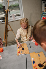 Girl mixed and combined colors. Education and learning concept. School kid drawing with brush on easel. Girl enjoys painting in a workshop. Art lesson. Children drew a picture in art class. Closeup.