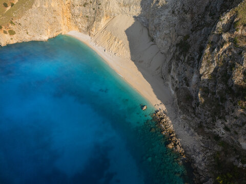 Aerial view of turquoise waters meeting a secluded beach embraced by rugged cliffs, creating a serene coastal haven, Agia Kiriaki, Cephalonia, Greece.