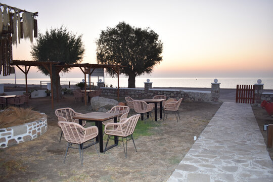 Summer sunrise landscape, Afandou village, Rhodes Island, Greece. Sea beach sunrise. Tourism and beach holidays. Travel to Greece. Empty Greek beach bar in the morning. Tables and chairs. 