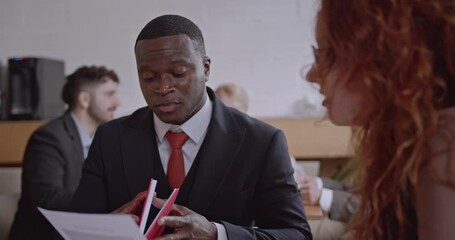 Diverse colleagues discuss analysis and brainstorm ideas in a coffee bar at a co-working space. The team collaborates on a project, reviewing notes and sharing insights. - Powered by Adobe