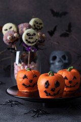 Variety of sweets treat for Halloween - pumpkin-shaped mousse cakes, cake pops skeletons and monsters with chocolate
