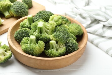 Fresh green broccoli in bowl on white wooden table, closeup