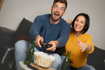Gamers enjoying playing video games indoors sitting on the sofa