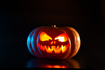 Halloween pumpkin with a scary glowing face on a black background.