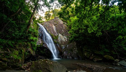 A long-exposure captures a waterfall cascading over a rocky cliff into a serene pool surrounded by lush greenery