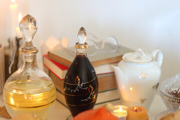Lit candles, cookies, chocolate, nuts, tea, wine, pumpkins, books, reading glasses and autumn leaves on the table. Autumnal hygge at home. Selective focus.
