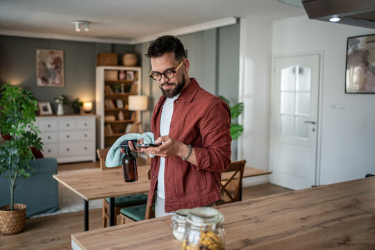 Man multitasking cleaning his home using smartphone - Powered by Adobe