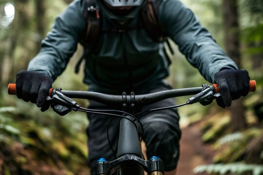 Mountain biker's hands in gloves holding handlebars, navigating a lush green forest path during an outdoor adventure sport - Powered by Adobe