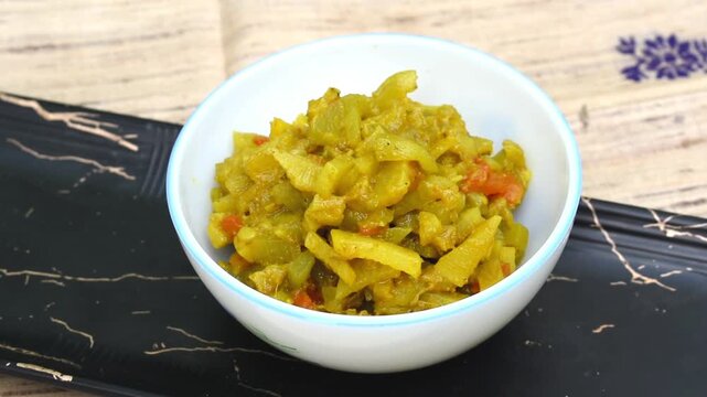 white bowl filled with Lauki ki Sabji or bottle gourd stir-fry, served on a black tray. 