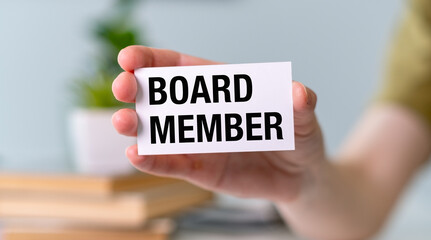 A person holding a white Board Member card. The person is holding the card in their hand