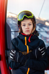 Portrait of confident pensive teenager kid boy enjoy having fun sit ski lift gondola at alpine mountain skiing resort on bright winter day. Teen beginner skier rest of training in ski school