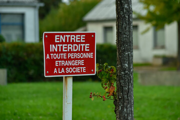 Red No Entry sign in French, translating to Entry forbidden to any person strange to the society. Highlights themes of exclusion, rules, and social boundaries.