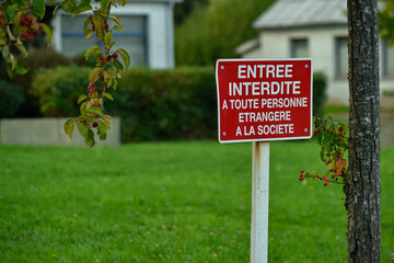 The red No Entry sign in French, meaning Entry forbidden to any person strange to the society. Framed by autumn foliage, highlighting social themes.