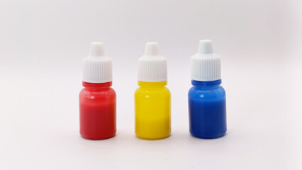 three colorful bottles (red, yellow and blue) on a white background with eye level angle