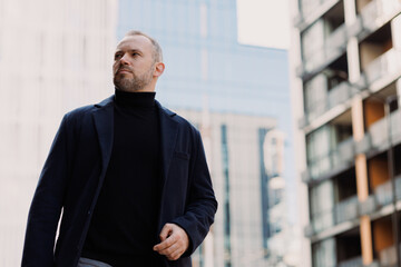 Man in elegant clothes and coat walking on city street 
