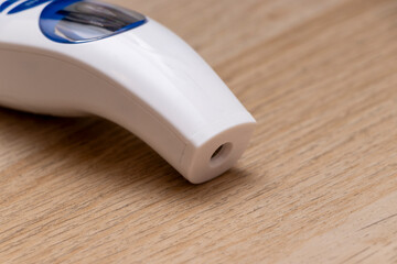 A close-up view of a white device designed for nasal application, featuring a transparent window and a plastic body, depicted on a light wood surface for context.