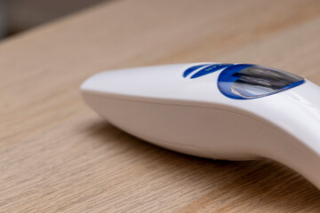 A modern handheld steam iron rests on a wooden surface, showcasing its sleek white design with a blue accent. Ideal for home and lifestyle applications.