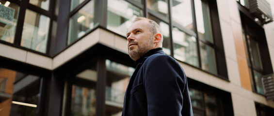 Web banner of businessman in coat standing near building outdoors 