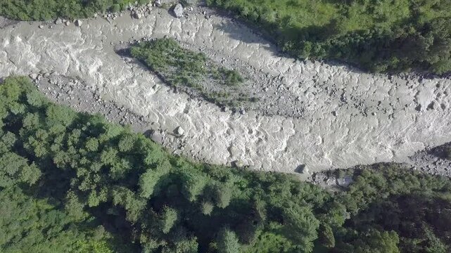 Drone shot of the Parvati River flowing between mountains at Kasol, Himachal Pradesh, India. Scenic view of the river during winter surrounded by natural mountain landscapes.