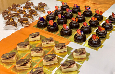chocolate eclairs ,strawberry mousse, domes, meringue, sited on the table, edible gold flakes in top, wrapped in paper