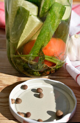 Pickled Cucumbers and Tomato with Herbs and Spices in Glass Jar on Wooden Table