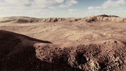 Stunning view of a vast desert landscape with rocky formations and rolling hills under a clear sky at dusk. The warm colors of the terrain contrast beautifully with the soft clouds.