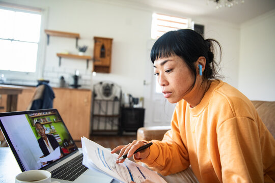 Adult woman attending online meeting at home with documents and coffee