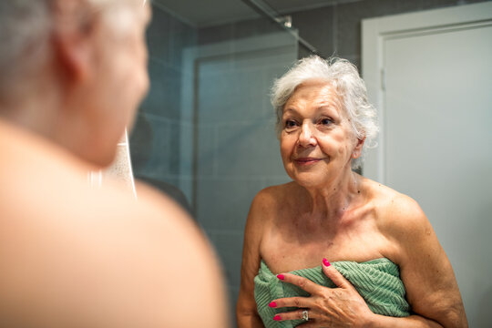 Senior woman looking at herself in the bathroom mirror