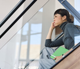 Fototapeta premium Portrait of a young businesswoman sitting on stairsin office, with headache, sick, tired or fatigue while working late . Burnout, stress and deadline concept