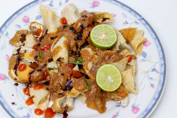 Delicious Indonesian Batagor, a street food dish of fried fish dumplings and tofu served with rich peanut sauce and a squeeze of lime