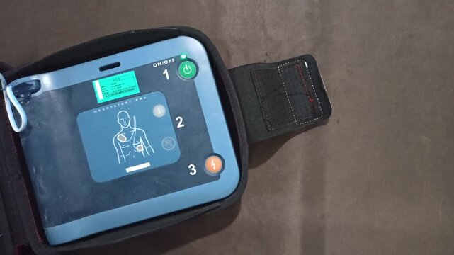 pressing the AED's shock button to deliver an electric shock to a heart attack patient
