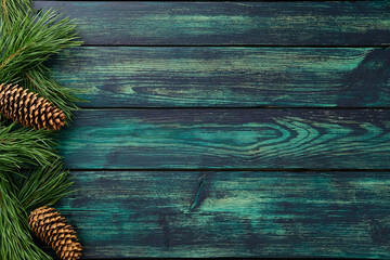 Rustic wooden background with pine branches and cones. Natural Christmas composition for seasonal greeting, festive card, or winter decoration design.