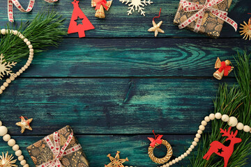 Christmas flat lay with gift box, wooden ornaments, pine branches and festive decor on rustic teal background, perfect for holiday greeting or seasonal design.